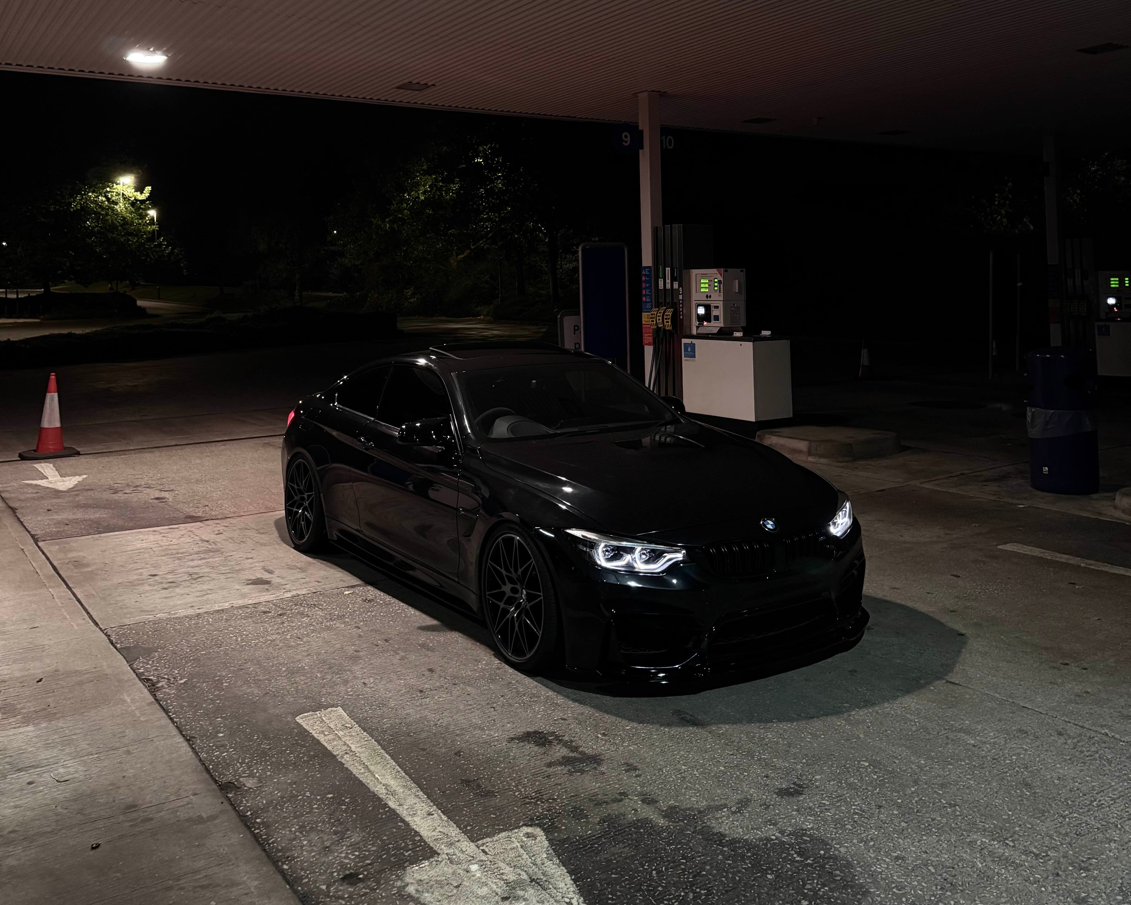 black bmw m4 parked at a gas station at night time with ikon headlights